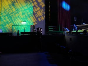 Operadora de cámara fotografiando el escenario de un evento, imagen original de Foreground